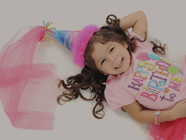 Young girl wearing a birthday hat and top